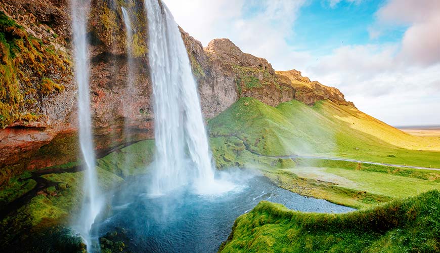 Seljalandsfoss waterfall in summer in iceland alongside green fields